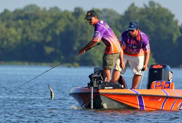 The fish jumps near the bow of the boat.