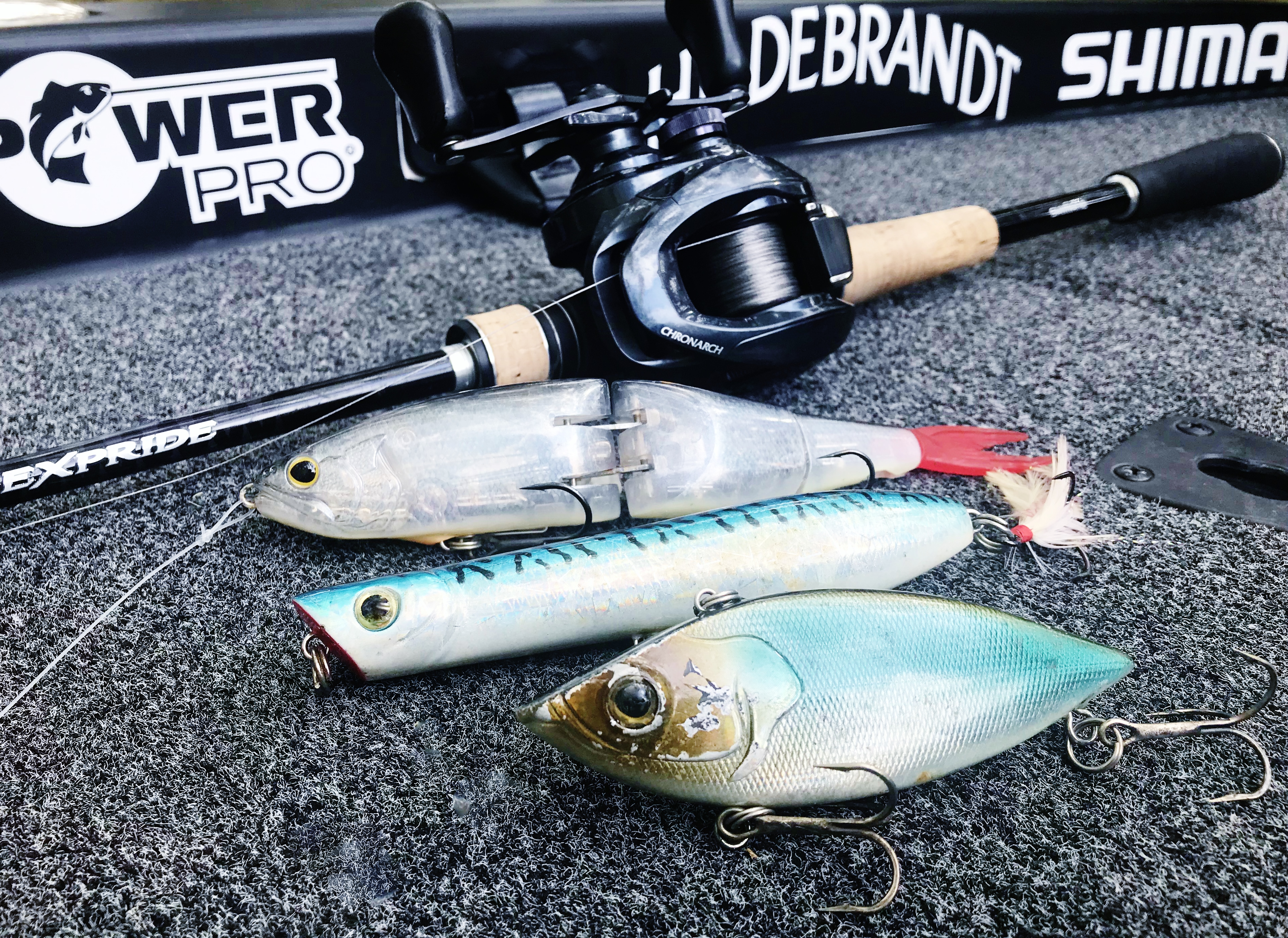 Large bass lures lined up on a boat carpet